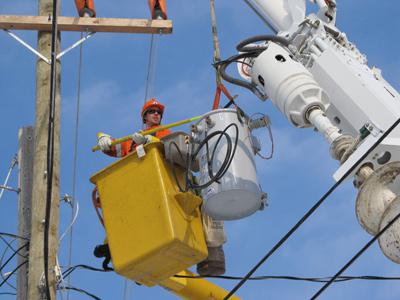 A worker in a cherry picker working on a power line.