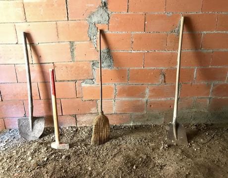 shovels and broom along brick wall